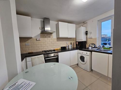 a kitchen with white cabinets and a table in it at London E14 Stay in London