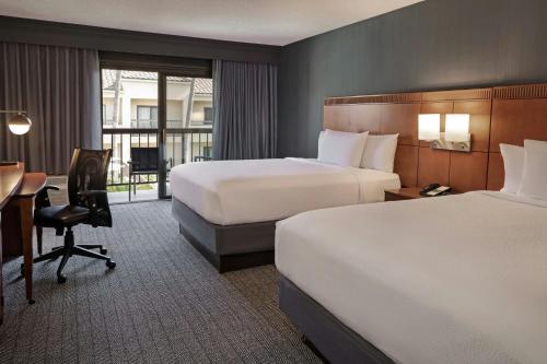 a hotel room with two beds and a desk at Courtyard Anaheim Buena Park in Buena Park
