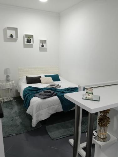 a white bedroom with a bed and a table at O Aconchegadinho in Rabo de Peixe