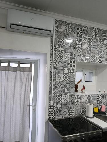 a kitchen with a tiled wall with a stove at O Aconchegadinho in Rabo de Peixe