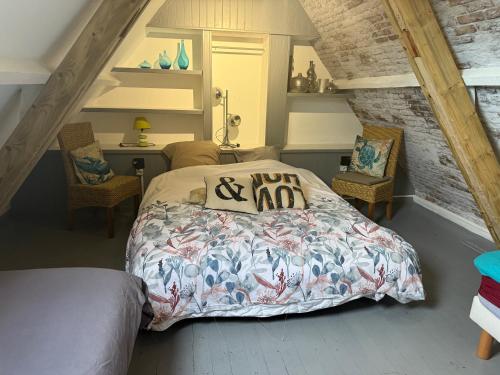 a bedroom with a bed with a comforter and two chairs at gites de Warincthun in Audinghen