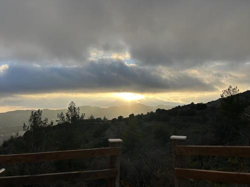 a view of the sunset from a hill with a bench at Cherry Holiday House in Khandria
