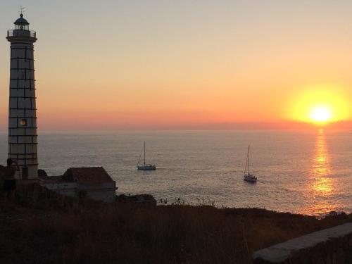 a lighthouse at sunset with boats in the water at Residence Timeo in Ustica