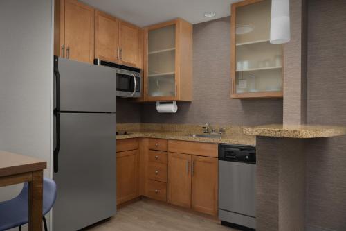 a kitchen with a white refrigerator and wooden cabinets at Residence Inn Phoenix North Happy Valley in Phoenix
