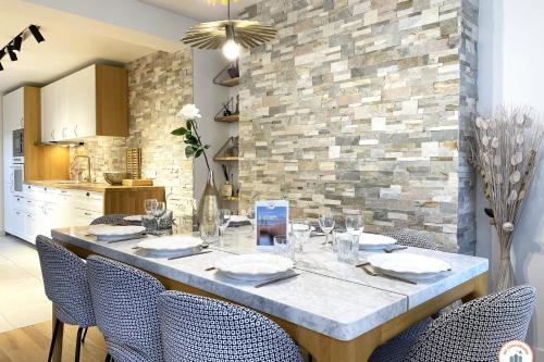 a dining room table with chairs and a stone wall at The Garden House - Jardin Parking Hypercentre in Deauville