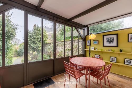une salle à manger avec une table, des chaises et des fenêtres dans l'établissement La Véranda Enchantée 4 - Garden - Fireplace - City Center - 6P, à Honfleur