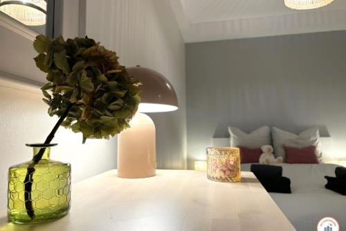 un vase avec une fleur sur une table à côté d'un lit dans l'établissement Les Bains de Trouville - Standing - Hypercentre, à Trouville-sur-Mer