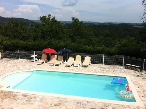 - une piscine avec des chaises et des parasols sur le sable dans l'établissement Gîte de France à Meyssac 4 épis - Gîte de France 12 personnes MAE-9024, à Meyssac