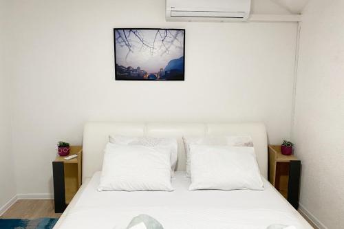 a bedroom with a white bed with two pillows at Farah Apartment in Mostar