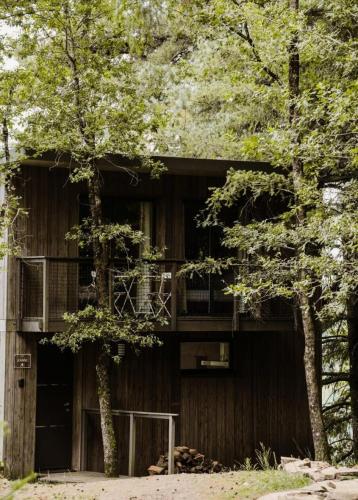 - un bâtiment en bois avec un balcon et des arbres dans l'établissement Gîte de France Jeanne 4 épis - Gîte de France 4 personnes MAE-1491, à Palazinges