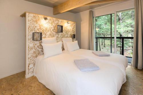 un grand lit blanc dans une chambre avec une fenêtre dans l'établissement Gîte de France Jeanne 4 épis - Gîte de France 4 personnes MAE-1491, à Palazinges