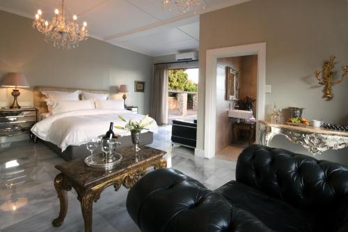 a bedroom with a bed and a couch and a table at The Gregoire Boutique Villa in Hermanus