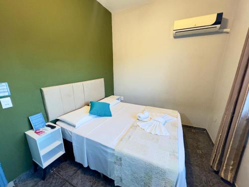 a bedroom with a white bed and a green wall at Pousada Cambará Suítes in Bonito