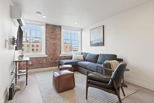 a living room with a blue couch and a brick wall at Roav Stays - J and K on Main Luxury Apartment 405 in Spokane