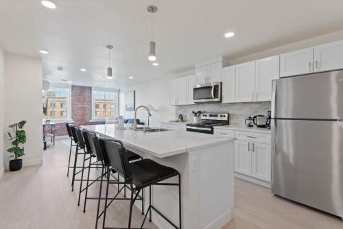 a kitchen with white cabinets and a large island with bar chairs at Roav Stays - J and K on Main Luxury Apartment 405 in Spokane