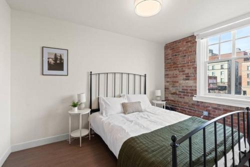 ein Schlafzimmer mit einem Bett und einer Ziegelwand in der Unterkunft Roav Stays - J and K Luxury Apartment 304 in Spokane