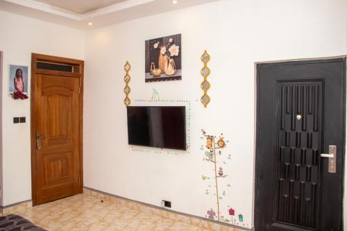 a living room with a television on a white wall at Kenest Villa - 3 Master-Bedrooms in Oyarifa