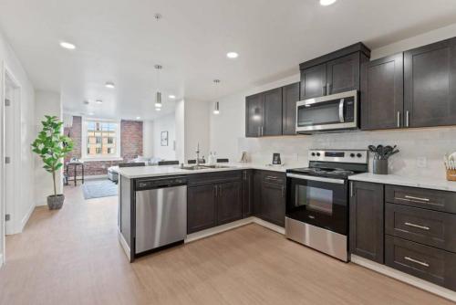 a large kitchen with black cabinets and stainless steel appliances at Walk to Riverfront Park! Downtown Gem w Pool Table 404 in Spokane