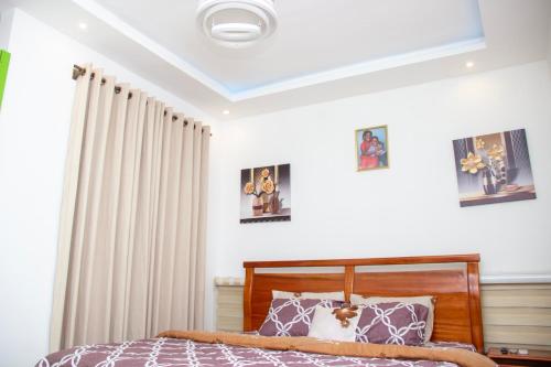 a bedroom with a bed and some pictures on the wall at Kenest Villa - 3 Master-Bedrooms in Oyarifa