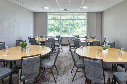 a room with tables and chairs and a large window at Courtyard Rochester East / Penfield in Rochester
