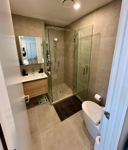 a bathroom with a shower and a toilet and a sink at Brand New Apartment CBD High Rise With Ocean View on the Doorstep of Courtenay Place in Wellington