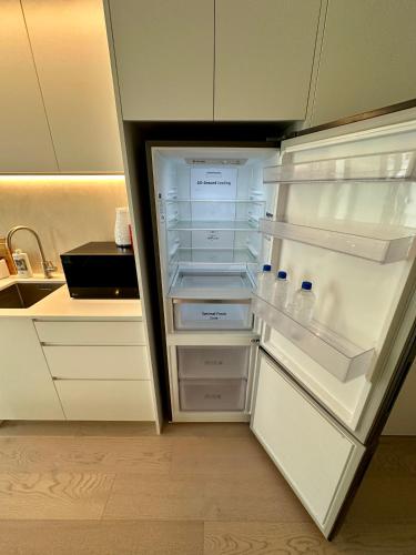 an empty refrigerator with its door open in a kitchen at Brand New Apartment CBD High Rise With Ocean View on the Doorstep of Courtenay Place in Wellington