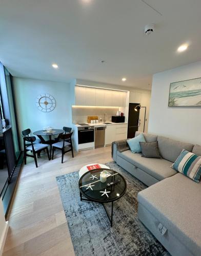 a living room with a couch and a table at Brand New Apartment CBD High Rise With Ocean View on the Doorstep of Courtenay Place in Wellington