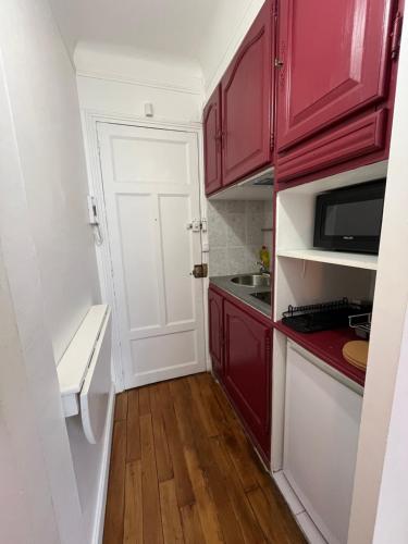 une cuisine avec des placards rouges et une porte blanche. dans l'établissement Magnifique appartement sacrée cœur, à Paris