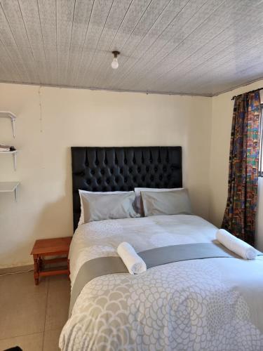 a bedroom with a large bed with a black headboard at Hideout in Highlands in Harare