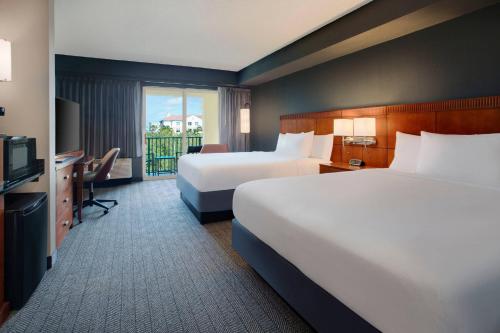 a hotel room with two beds and a television at Courtyard Fort Lauderdale SW Miramar in Miramar
