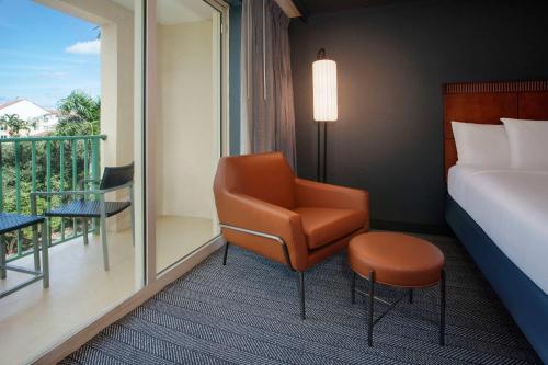 a room with a bed and a chair and a balcony at Courtyard Fort Lauderdale SW Miramar in Miramar