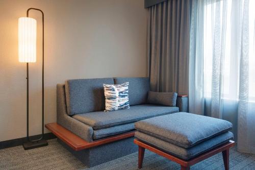 a living room with a blue chair and a ottoman at Courtyard Fort Lauderdale SW Miramar in Miramar