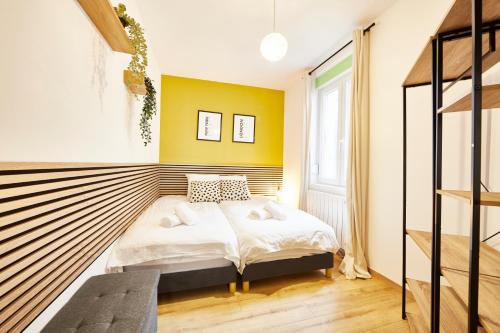 - une chambre avec un lit et un mur jaune dans l'établissement BE-0 - Appartement F1 pour 1-2 pers au RDC au centre de Mulhouse, à Mulhouse