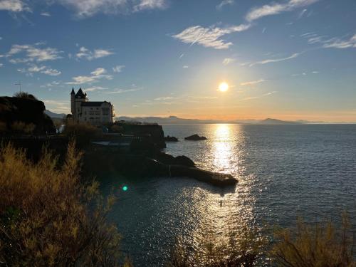 a sunset over a body of water with a castle at Maison Gure Chokoa Pays Basque in Bardos