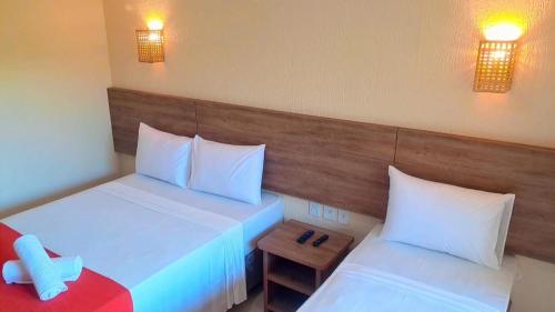a hotel room with two beds and a table at Ayla Praia Hotel Centro Porto Segur in Porto Seguro