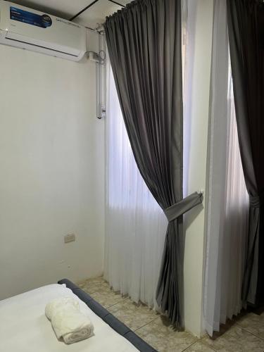 a bedroom with a bed and a window with curtains at 6 habitaciones, 10 camas, amplio y céntrico, 3 parqueos in Machala