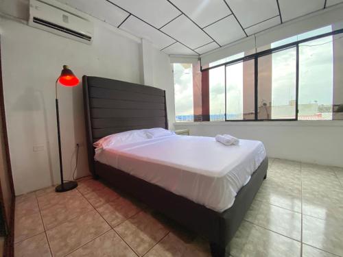 a bedroom with a bed and a lamp and windows at 6 habitaciones, 10 camas, amplio y céntrico, 3 parqueos in Machala