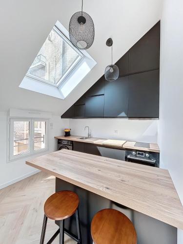 une cuisine avec un comptoir en bois et deux tabourets dans l'établissement Petit Loft centre-ville, à Épernay