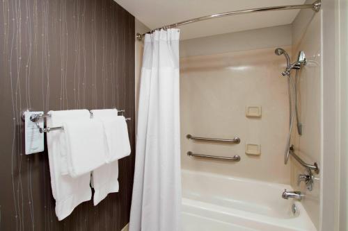 a bathroom with a shower and a bath tub with towels at Courtyard by Marriott Cocoa Beach Cape Canaveral in Cocoa Beach