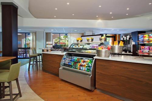 a restaurant with a counter with a drink refrigerator at Courtyard by Marriott Cocoa Beach Cape Canaveral in Cocoa Beach