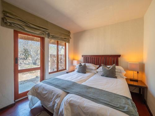 a bedroom with a large bed and a window at Shibula Safari Lodge in Welgevonden Game Reserve