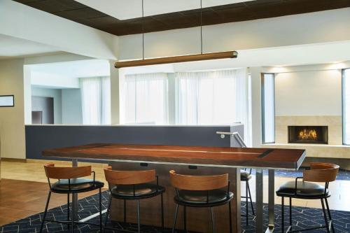 a bar in a room with chairs and a fireplace at Courtyard St. Louis Westport Plaza in Maryland Heights