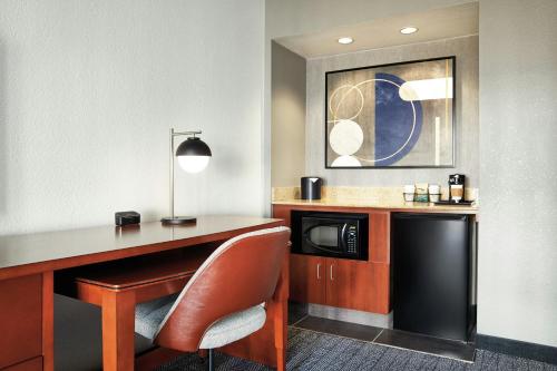 a desk with a chair and a microwave in a room at Courtyard St. Louis Westport Plaza in Maryland Heights