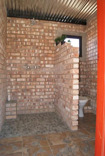 a brick bathroom with a toilet in a brick wall at Orpheus Inn Camping in Kaneb Pos
