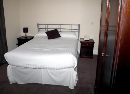 a bedroom with a white bed with a black pillow on it at Rose and Crown Hotel in Haverhill