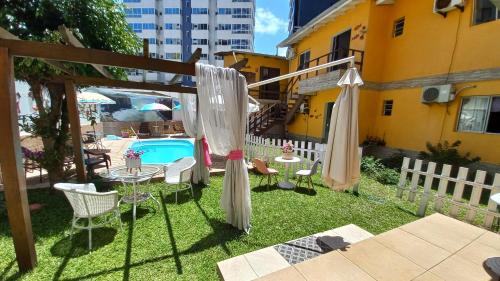 a backyard with a table and chairs and a pool at Cozinha Equipada em Apartamento para Alugar em Torres RS in Torres
