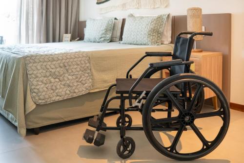 a black wheelchair in a bedroom with a bed at Hotel Velas do Engenho in Ilhabela