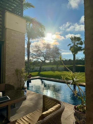 a patio with a pool with chairs and palm trees at Mazagan private villa in El Jadida