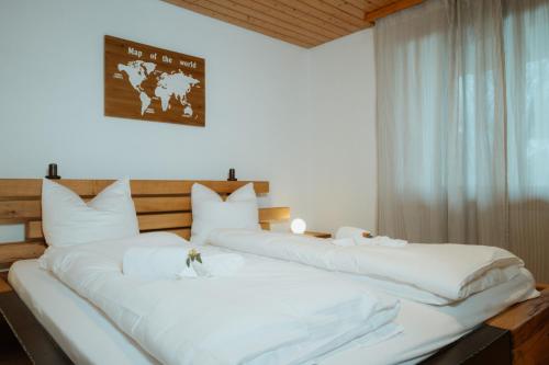 two large white beds in a room with a window at Apartment Bergzauber in Amden
