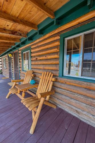 two wooden chairs sitting on the porch of a cabin at Chinook Winds Lodge in Dubois